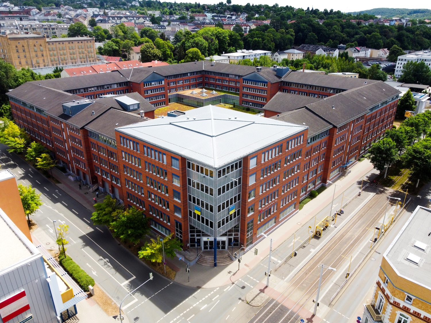 Ein großes rechteckiges Backsteingebäude mit Innenhof, umgeben von weiteren städtischen Bauten. Die Aufnahme zeigt eine Draufsicht.