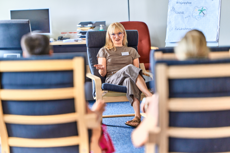 Frau in Gesprächsrunde mit zwei Personen.